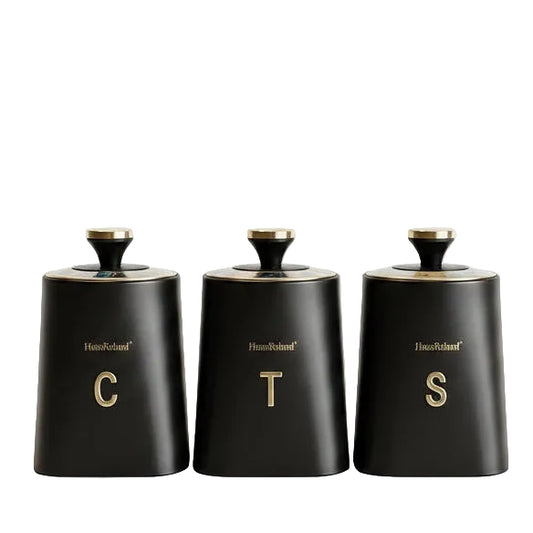 Haus Roland black matte 3 piece canister set with gold lettering for tea coffee and sugar on marble countertop