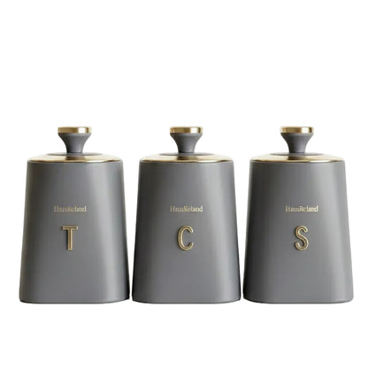 Haus Roland grey ceramic style canister set featuring elegant gold caps and gold T C S letters