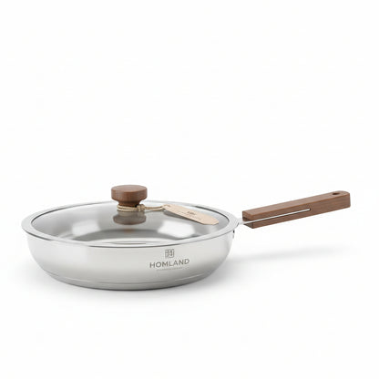HOMLAND 24cm 304 stainless steel frying pan with glass lid on a white marble kitchen countertop.