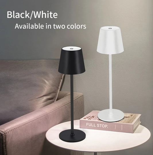 Two table lamps, one black and one white, on a table with a couch in the background.

