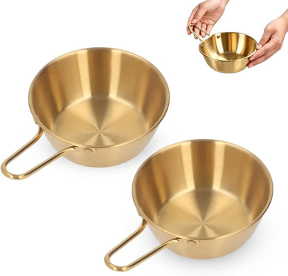 Korean stainless steel gold bowls filled with soup, rice, and ramen dishes on a table