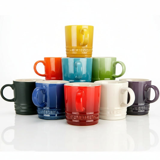Complete set of six colorful Le Creuset stoneware rainbow coffee mugs arranged neatly on a modern kitchen counter.