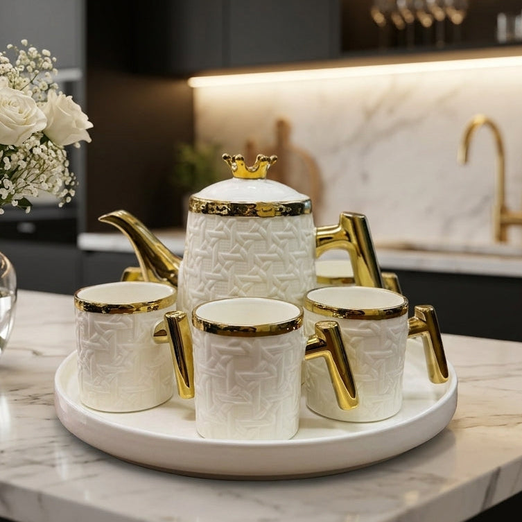 White and gold 8-piece ceramic revolving tea set with teapot and cups displayed on a marble kitchen island