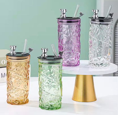 Four luxury bear glass tumblers in amber, green, purple, and clear textured finishes on display.