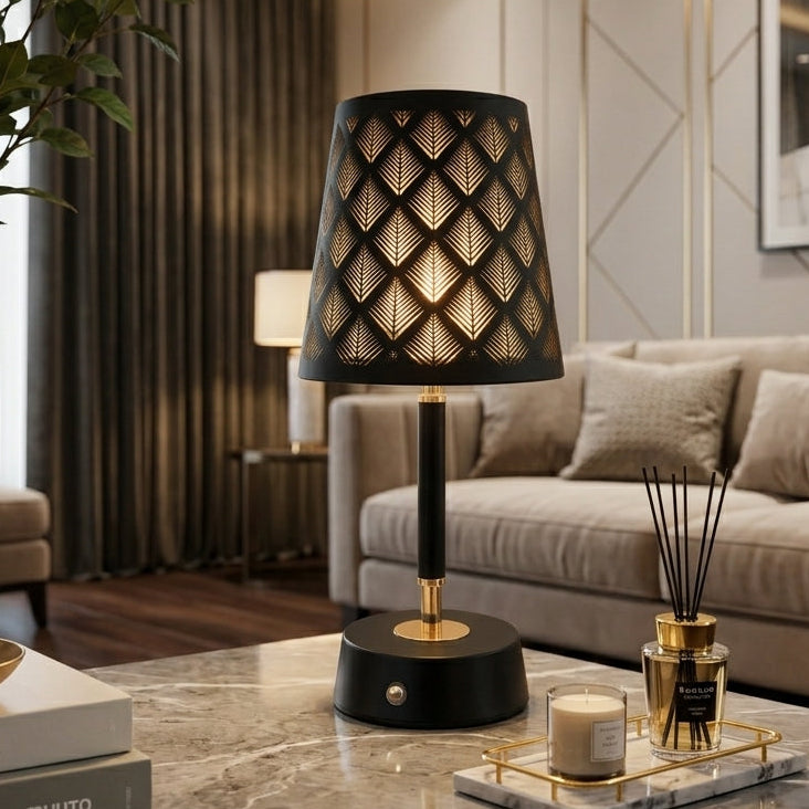 Black and gold metal table lamp with geometric leaf cutout shade on marble table