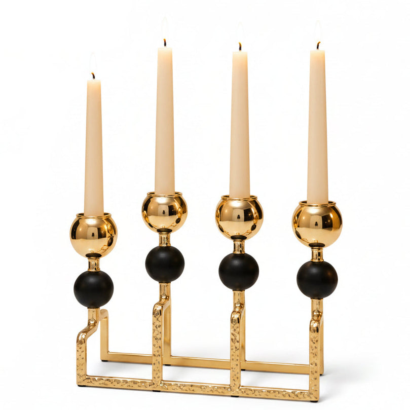 Luxury black and gold 4-arm candle stand centerpiece displayed on a minimalist white marble dining table.
