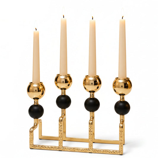 Luxury black and gold 4-arm candle stand centerpiece displayed on a minimalist white marble dining table.