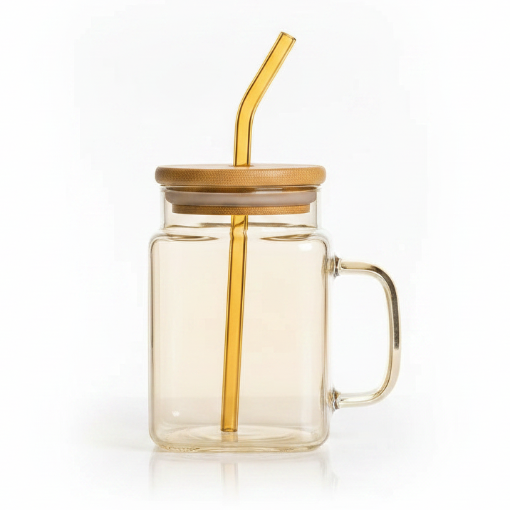 Luxury cube glass drinking mug in golden tint with matching glass straw placed on a table