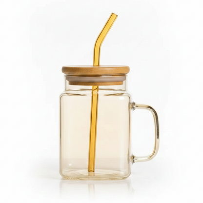 Luxury cube glass drinking mug in golden tint with matching glass straw placed on a table
