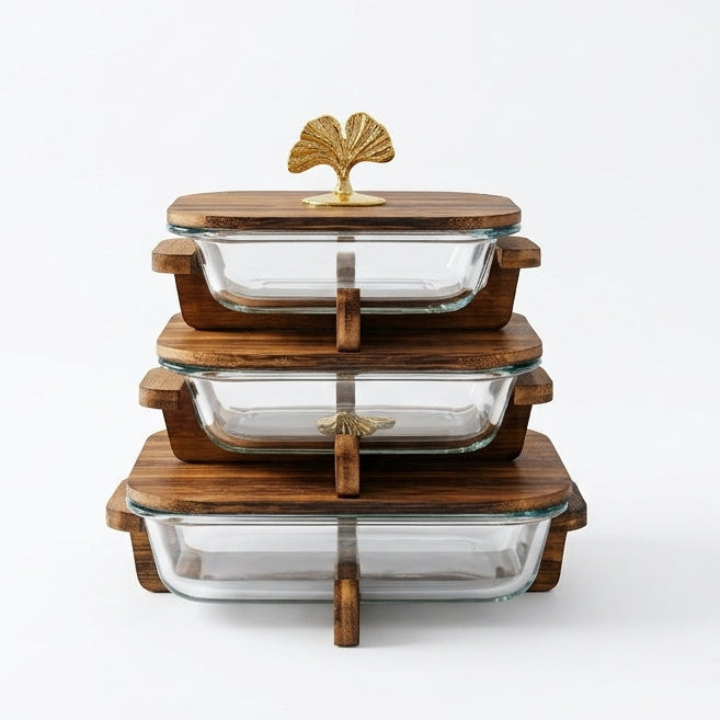 Stacked 3 piece clear glass casserole dishes with wooden lids and gold leaf handles