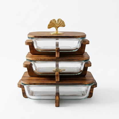 Stacked 3 piece clear glass casserole dishes with wooden lids and gold leaf handles