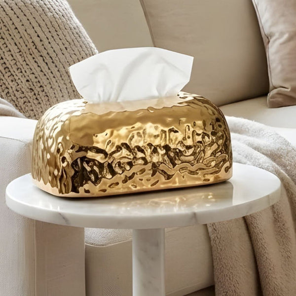 Luxury gold textured tissue box cover displayed on a wooden living room coffee table.
