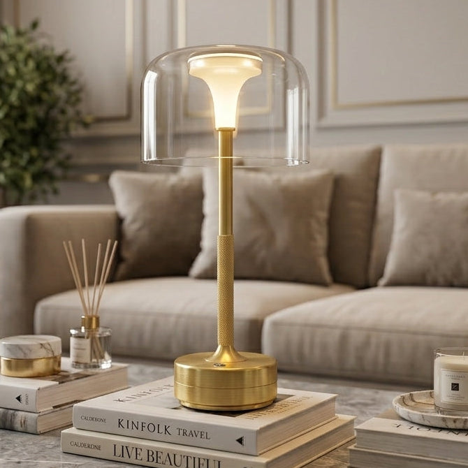 Brass minimalist glass shade LED table lamp lit on marble table in cozy room