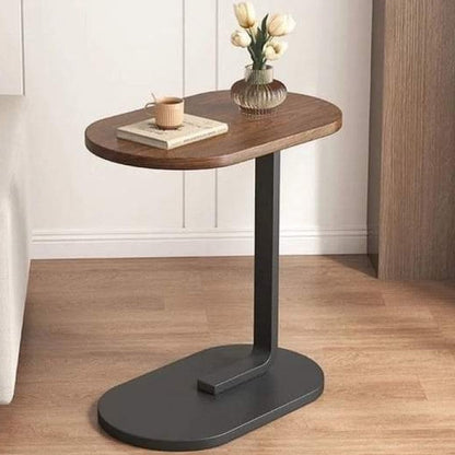 Multifunctional wooden side table placed next to a living room sofa holding a coffee mug and book.