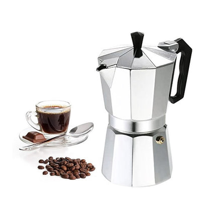 Freshly brewed rich espresso coffee poured into a glass cup next to a black Moka Pot.