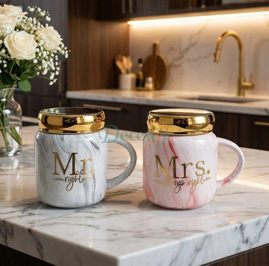 Pair of grey and pink marble Mr and Mrs ceramic coffee mugs with gold metallic lids placed on a marble kitchen counter.