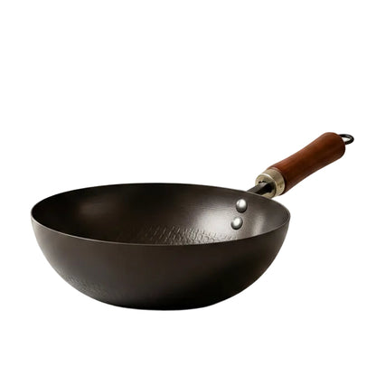 Black non-stick wok pan with wooden handle sitting on a marble kitchen countertop.