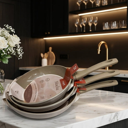 Stack of OSFE Mocha non-stick ceramic frypans on a marble kitchen countertop.