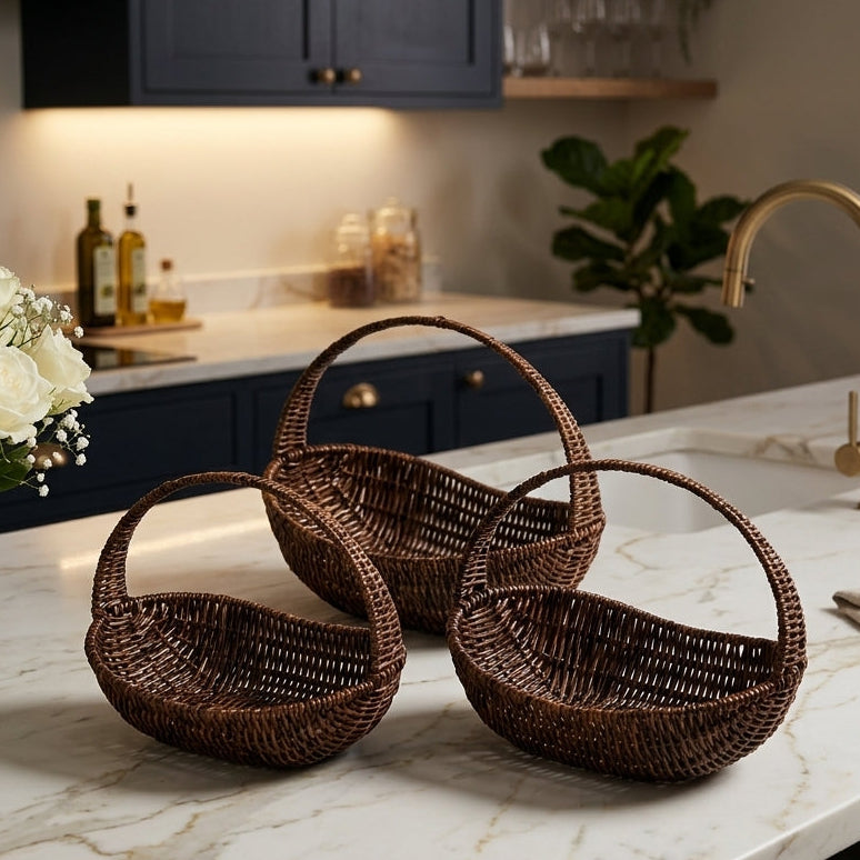 Three dark brown oval woven cane fruit baskets with handles resting on a marble kitchen island