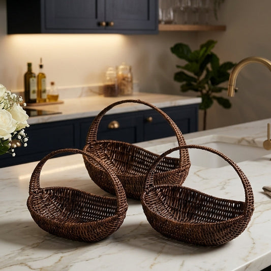Three dark brown oval woven cane fruit baskets with handles resting on a marble kitchen island