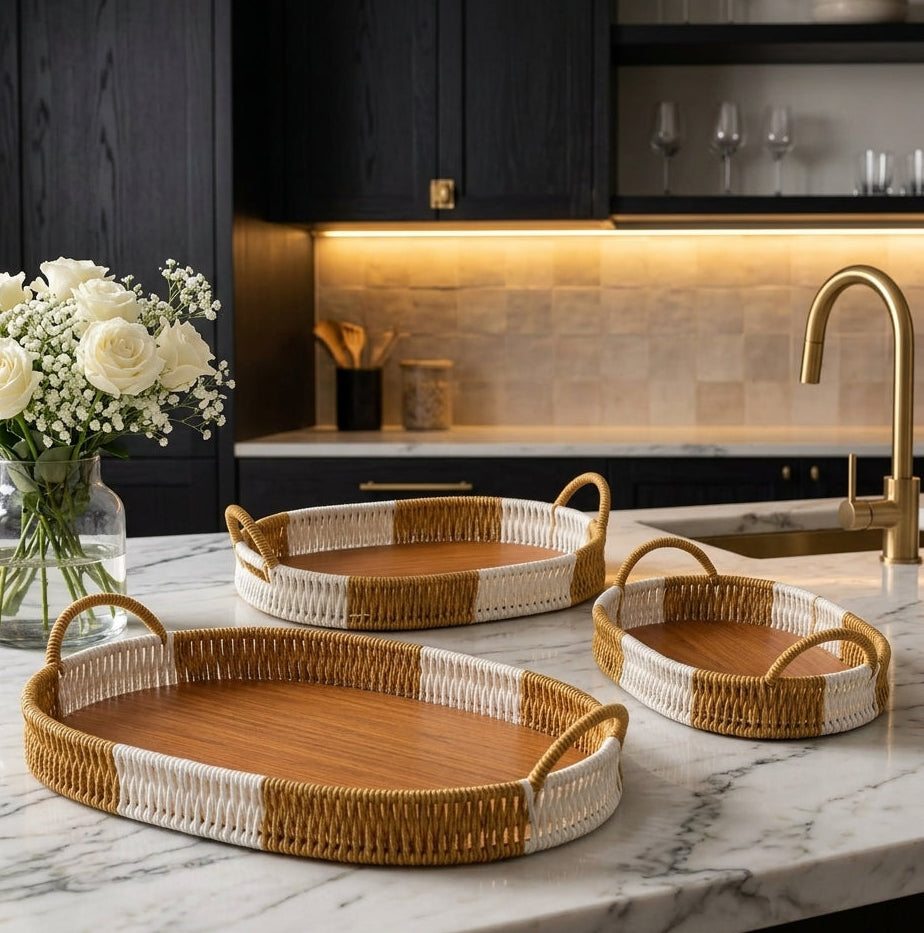 Set of 3 oval woven serving trays with wooden bases and side handles displayed on a marble countertop.