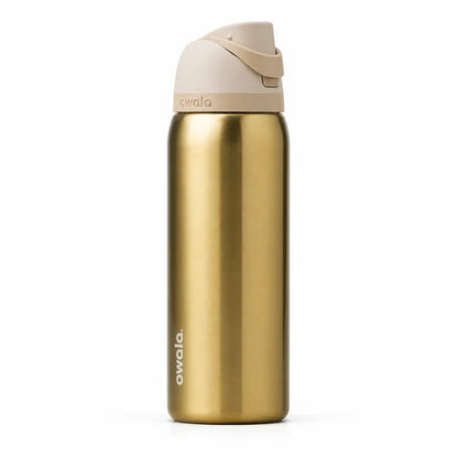 Owala FreeSip 32 oz stainless steel water bottle in Golden Tune shade sitting on a marble kitchen counter.
