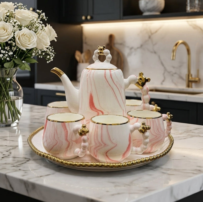 8-piece pink marble ceramic tea set with teapot and cups on a gold beaded revolving tray