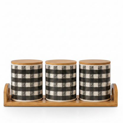Three plaid pattern ceramic kitchen storage canisters arranged neatly on a wooden tray.
