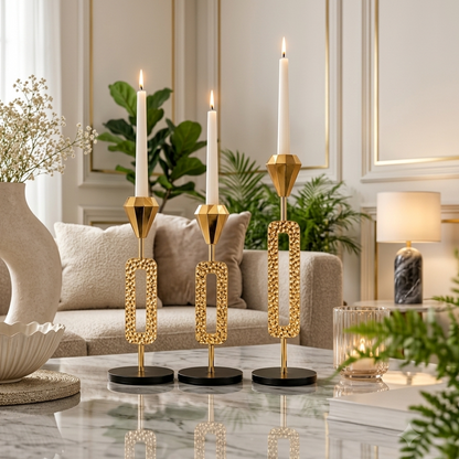 Three premium gold metal candle holders of varying heights displayed on a modern wooden coffee table.