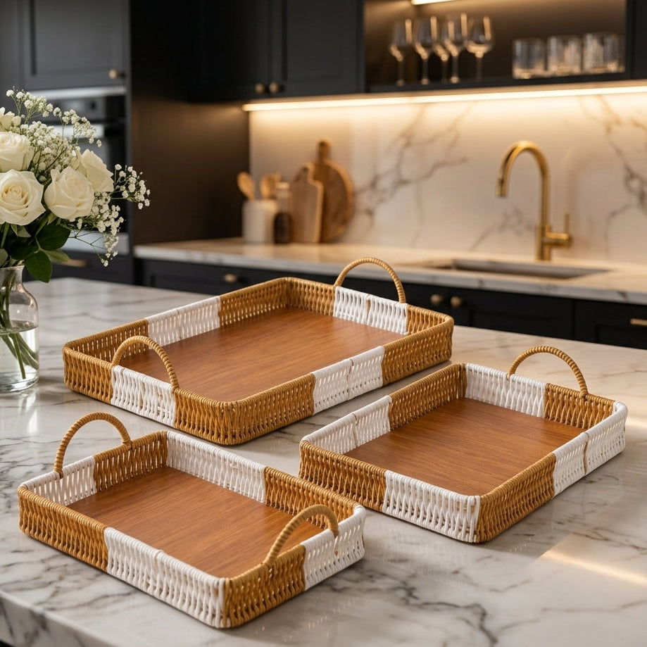 Set of 3 rectangular handwoven rattan serving trays with handles on a marble kitchen island   