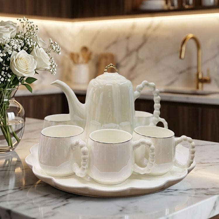8-piece revolving ceramic tea set with pearl handle cups arranged on a marble table.