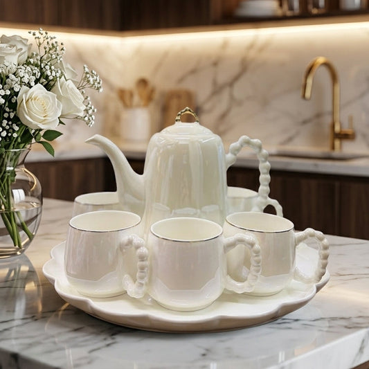 8-piece revolving ceramic tea set with pearl handle cups arranged on a marble table.