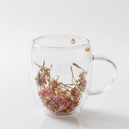 Rose Petal double wall clear glass mug with dried flowers inside resting on a woven coaster
