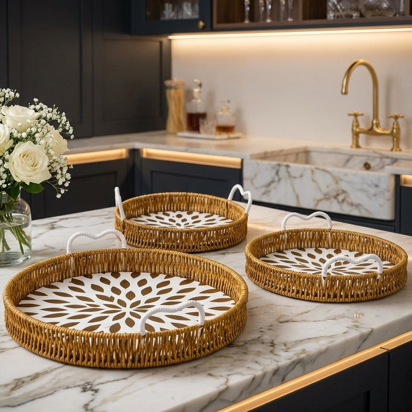 Set of three round rattan serving trays with white handles on a marble kitchen counter