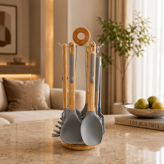 Grey silicone kitchen utensils set with wooden handles and a matching holder arranged on a marble kitchen counter