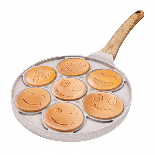 Person flipping a cooked mini smiley face pancake with a white silicone spatula on a non-stick pan.
