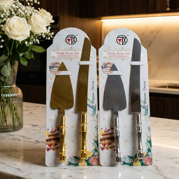 Two retail packs of stainless steel cake server and knife sets displayed on a marble countertop next to a white flower vase.