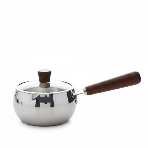 Stainless steel saucepan with a dark wooden handle and glass lid on a marble kitchen counter.