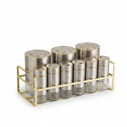 9-piece stainless steel spice jar set with gold stand arranged on a marble kitchen countertop