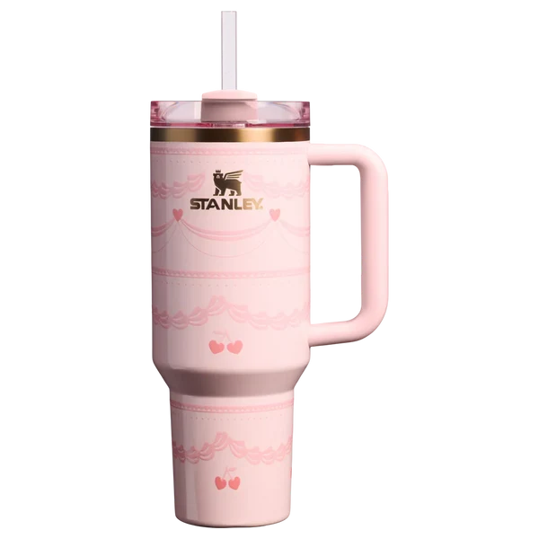 Pink Stanley Quencher 40oz tumbler with ribbon and cherry print standing on a marble kitchen island counter.