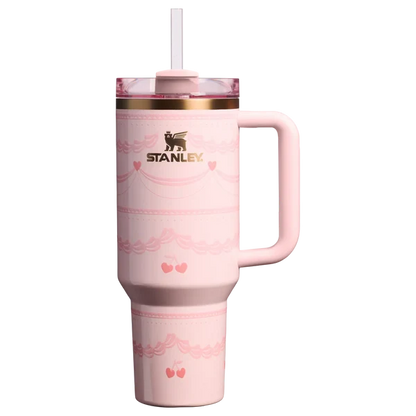 Pink Stanley Quencher 40oz tumbler with ribbon and cherry print standing on a marble kitchen island counter.