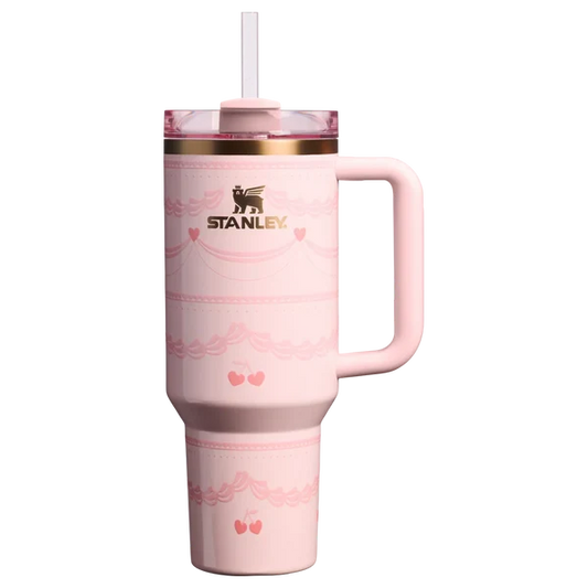 Pink Stanley Quencher 40oz tumbler with ribbon and cherry print standing on a marble kitchen island counter.