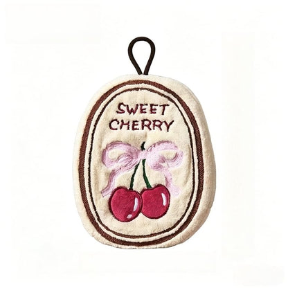 Woman drying her hands on a soft beige hanging hand towel featuring an embroidered cherry design