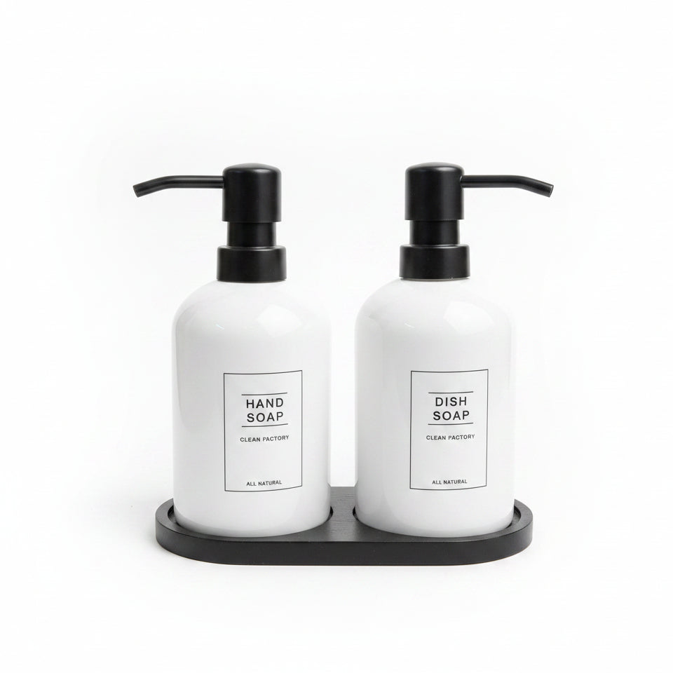 White ceramic hand soap and dish soap dispenser set sitting on a black tray.