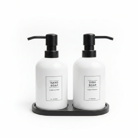 White ceramic hand soap and dish soap dispenser set sitting on a black tray.