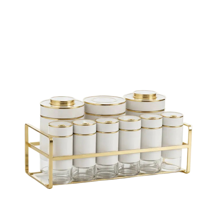 Luxury white spice containers with gold-rimmed caps organized on a gold metal stand set on a marble kitchen counter.