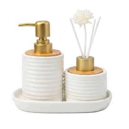White ribbed ceramic soap dispenser and reed diffuser with flower sticks sitting on a ceramic tray.